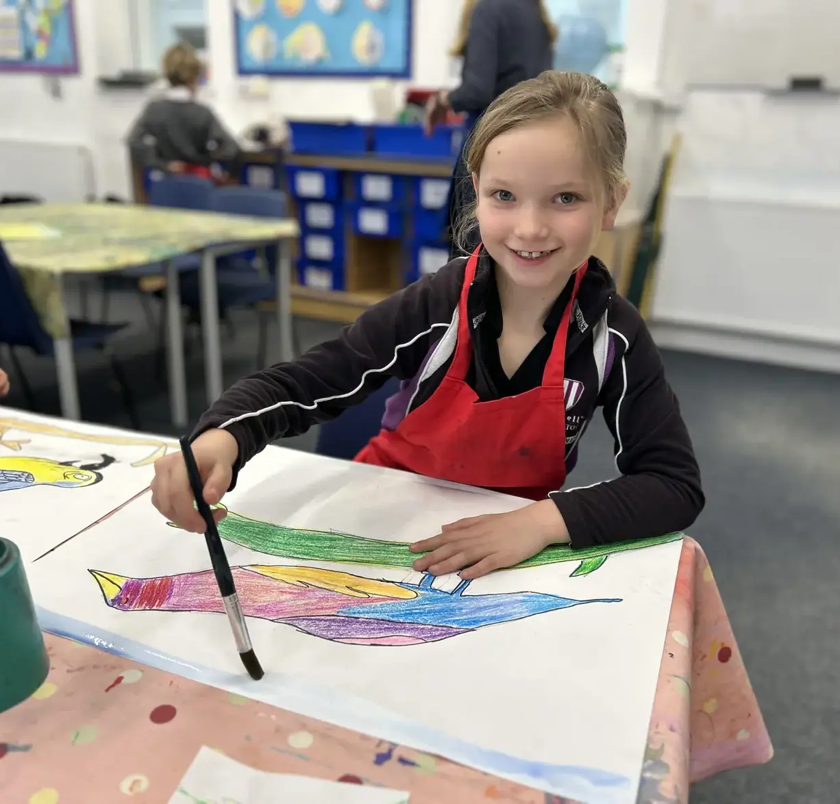 Student smiling up from painting