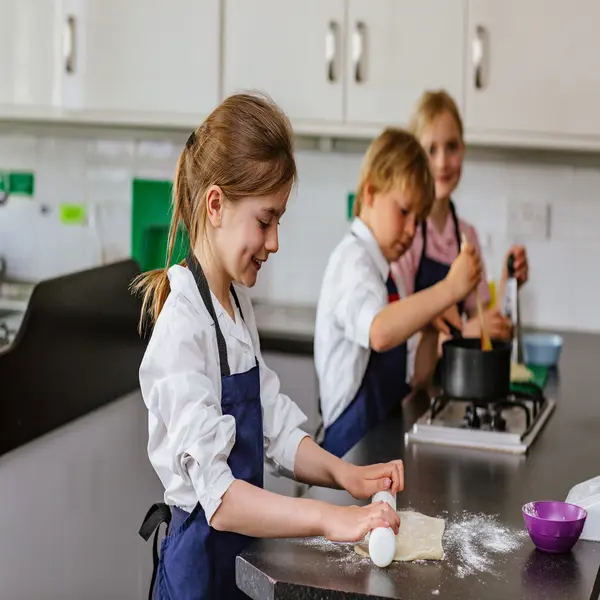 pupils smiling and cooking in the kitchen blundells pre school private prep school in devon