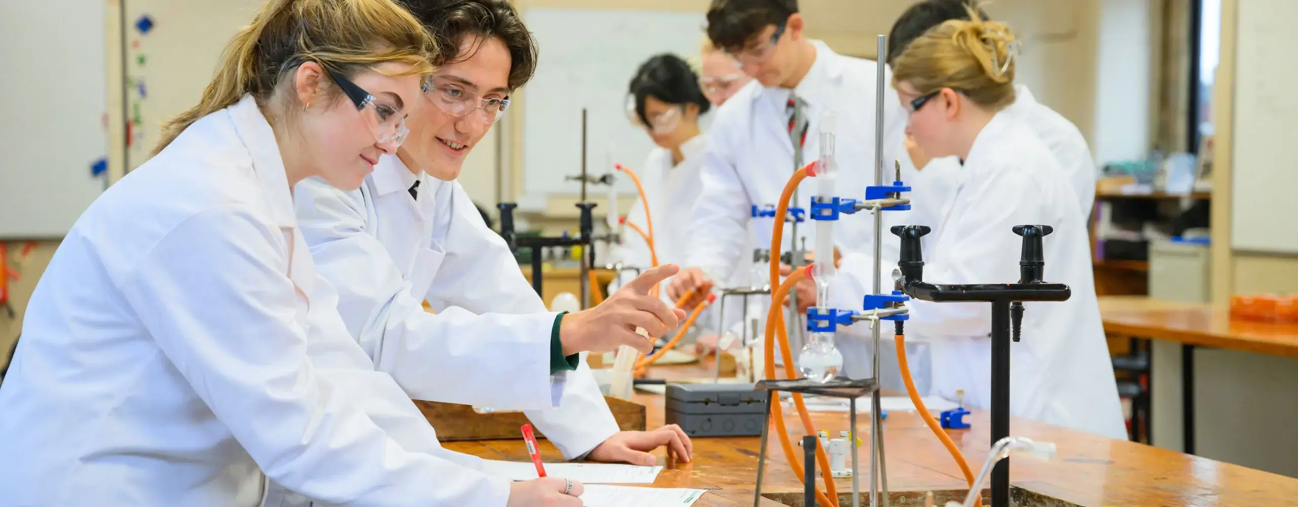 Students wearing lab coats in science lesson