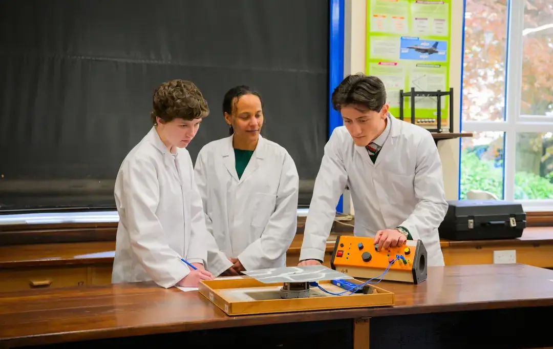 Three students wearing labcoats working on a project