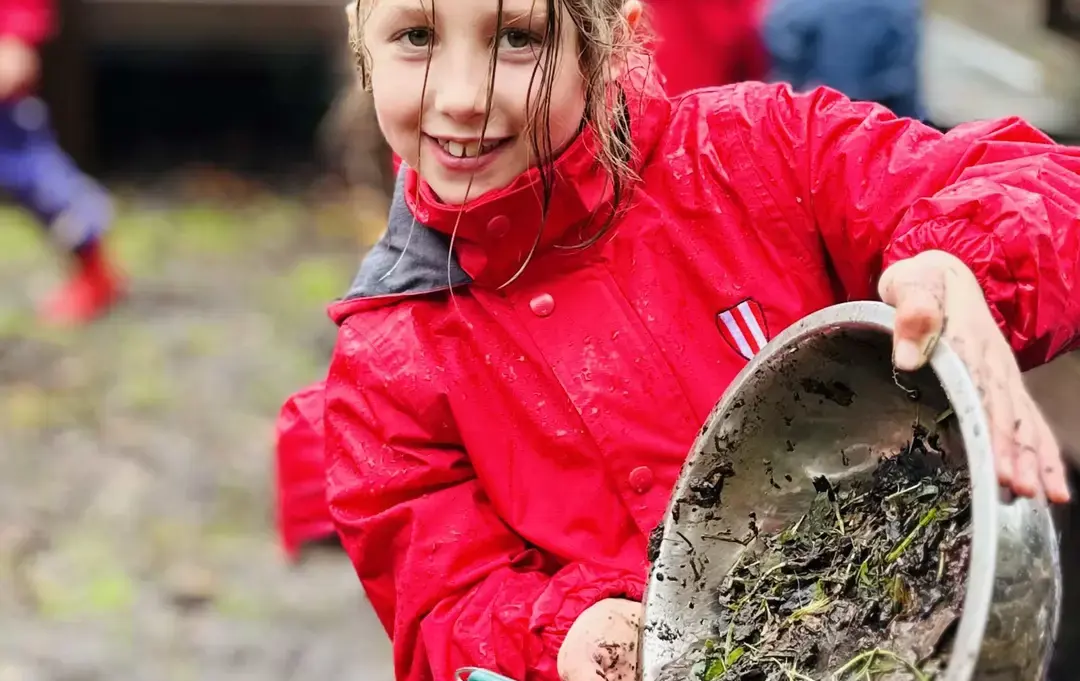 Student showing off bucket full of muck