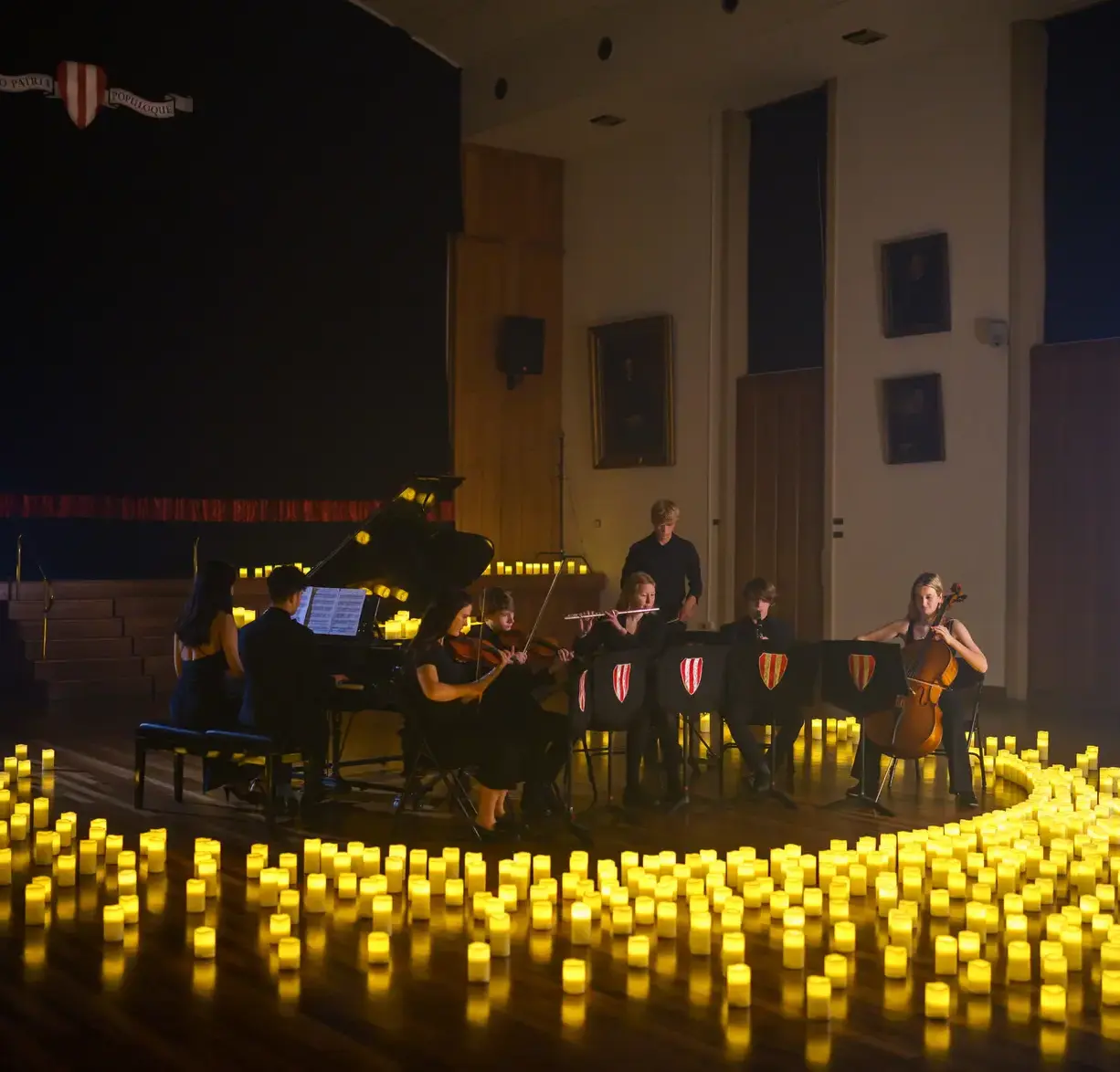 Student orchestra playing, surrounded by candles
