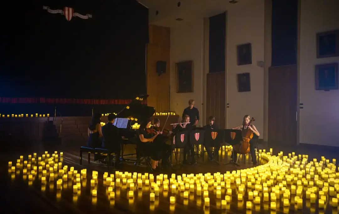 Student orchestra playing, surrounded by candles