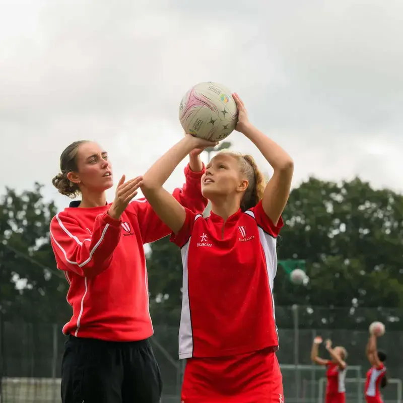 netball teacher coaching pupil on netball courts at blundells school private school in devon